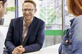 Ein Berater ist im Gespräch mit einem jungen Paar.